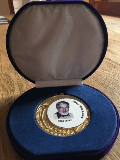 Zu sehen ist eine gold-weiße Medaille mit einem Portrait von Dieter Möhl. Diese Medaille wurde als Award an Dr. Fritz Caspers verliehen. Die Medaille liegt in einer blauen Schatulle. © privat/Caspers